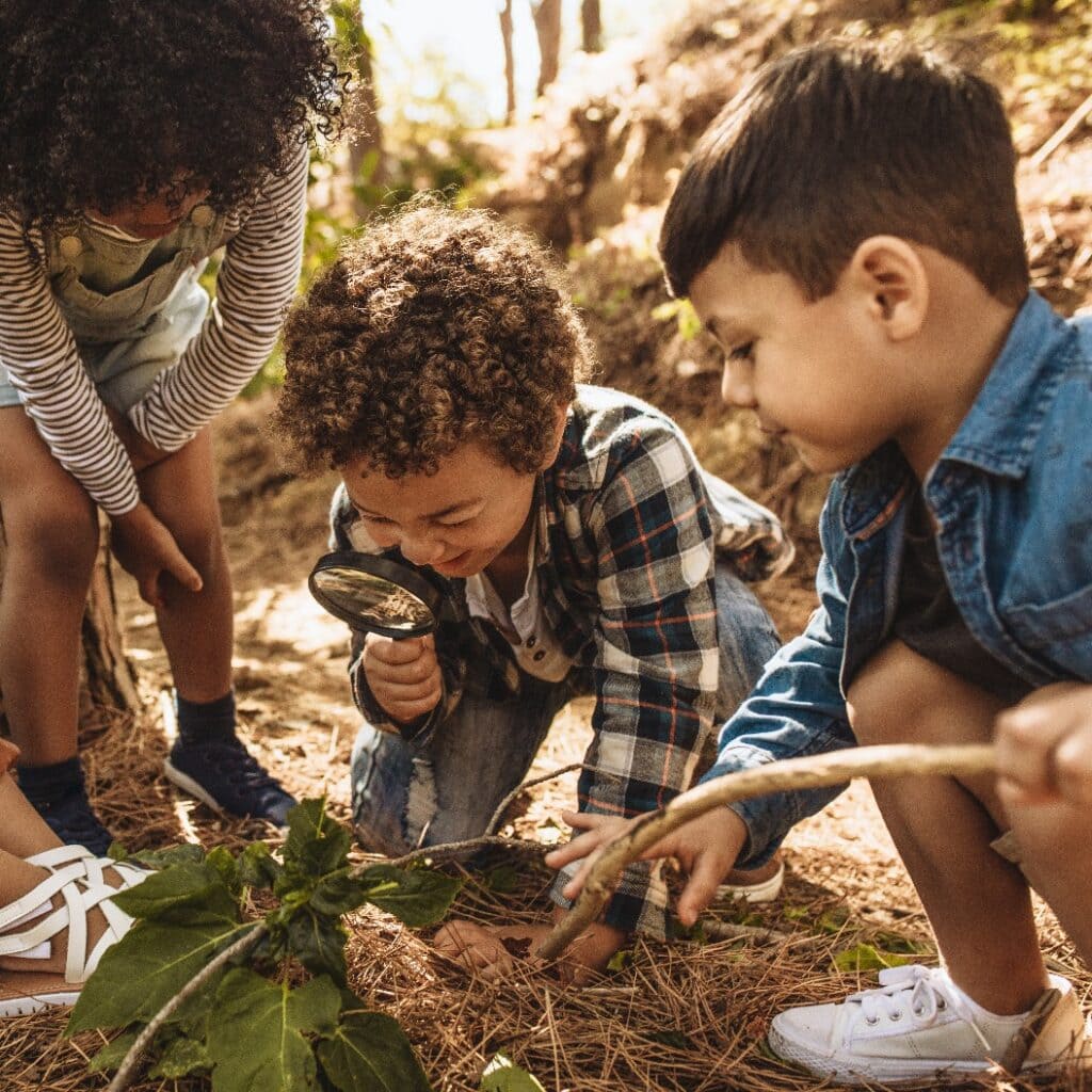 Kids exploring in forest with a magnifying glass